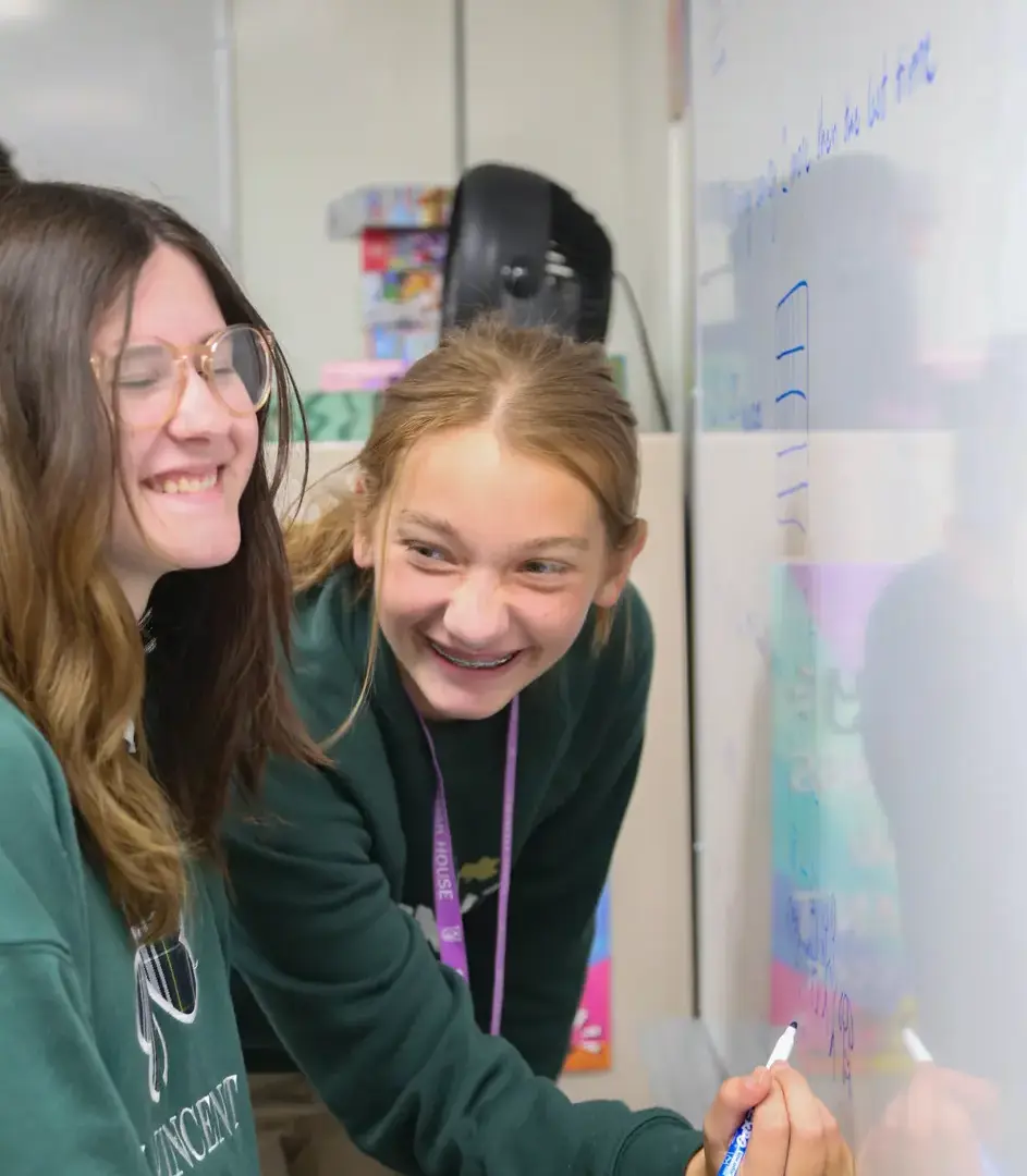 STVM students writing an answer on the whiteboard, smiling and laughing.
