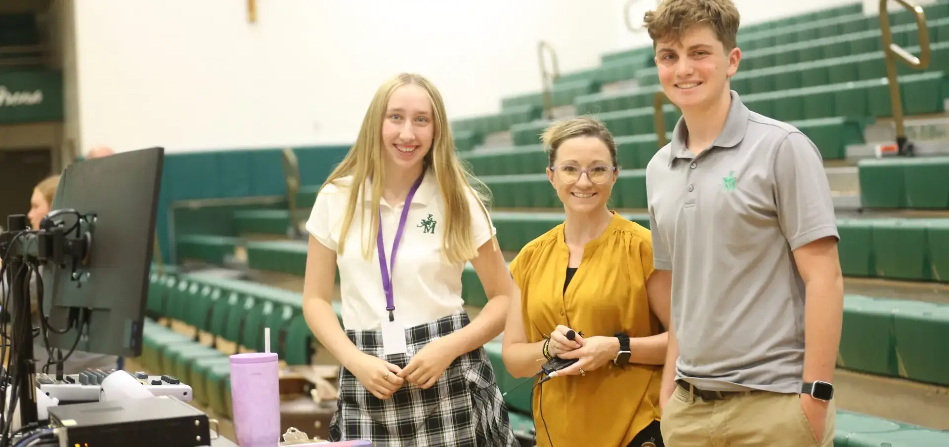STVM students and teacher smiling, standing by seating in the gymnasium.