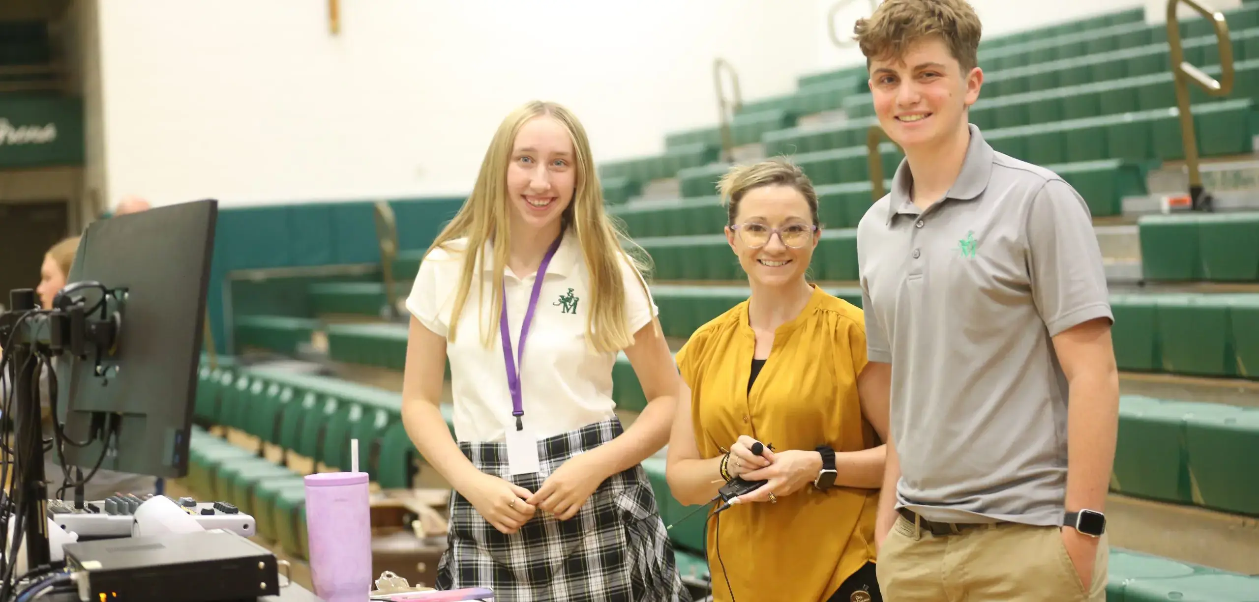STVM students and teacher smiling, standing by seating in the gymnasium.