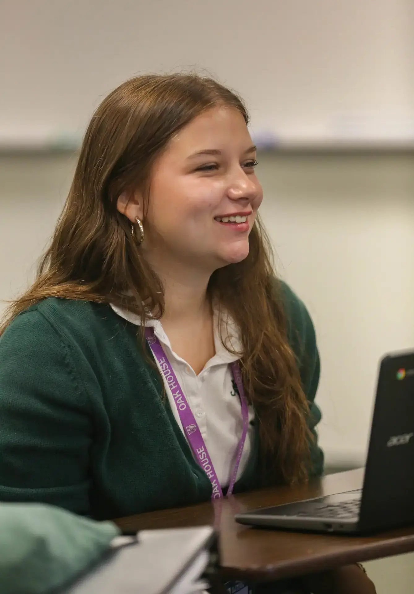 STVM student smiling in class, working on a laptop.