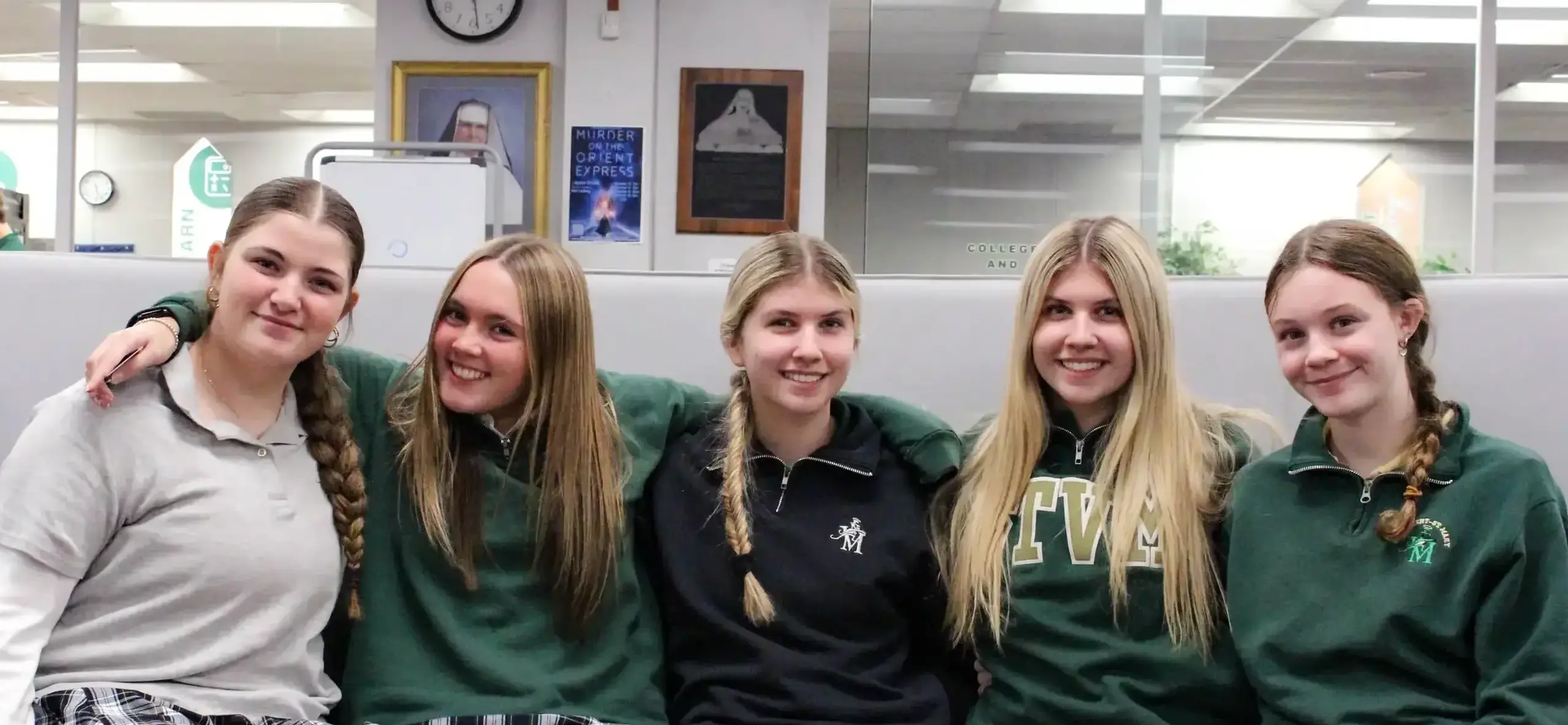STVM students sitting together, arm in arm, smiling brightly for a photograph.