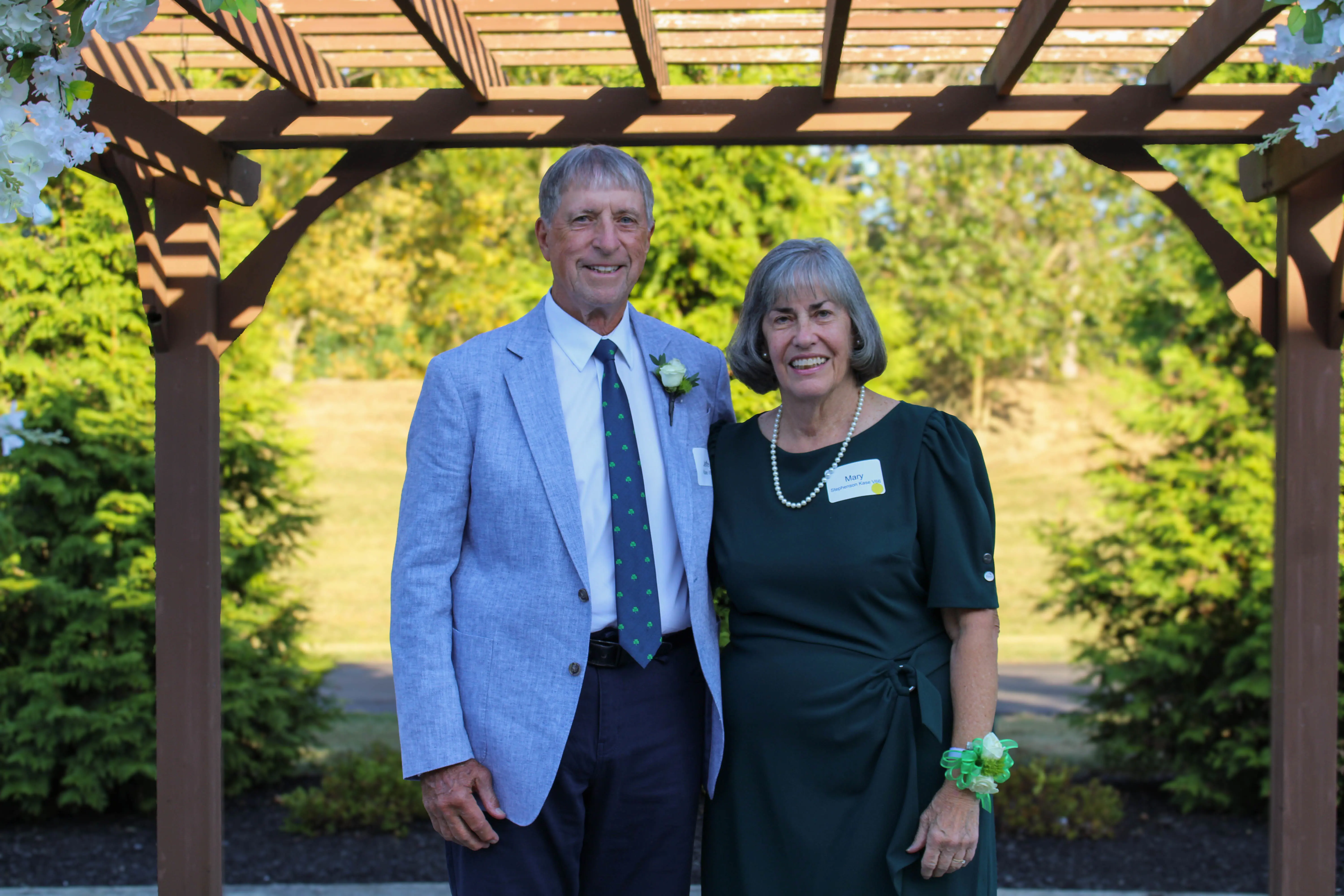 Recipient of the Fr. Mahar Award standing under a trellis in a garden.