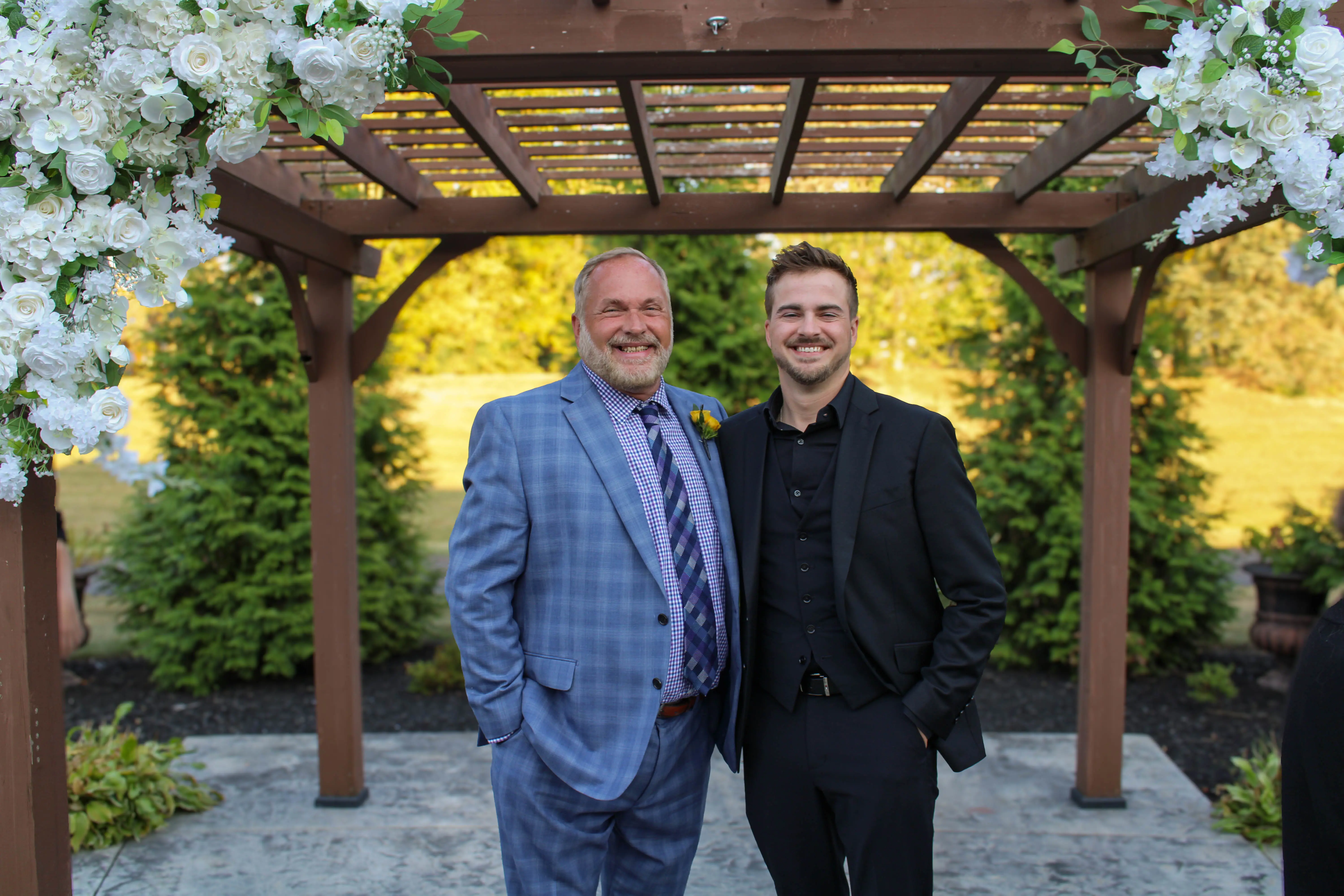Recipients of the Irish Crusader Award standing under a trellis decorated with white roses in a garden.