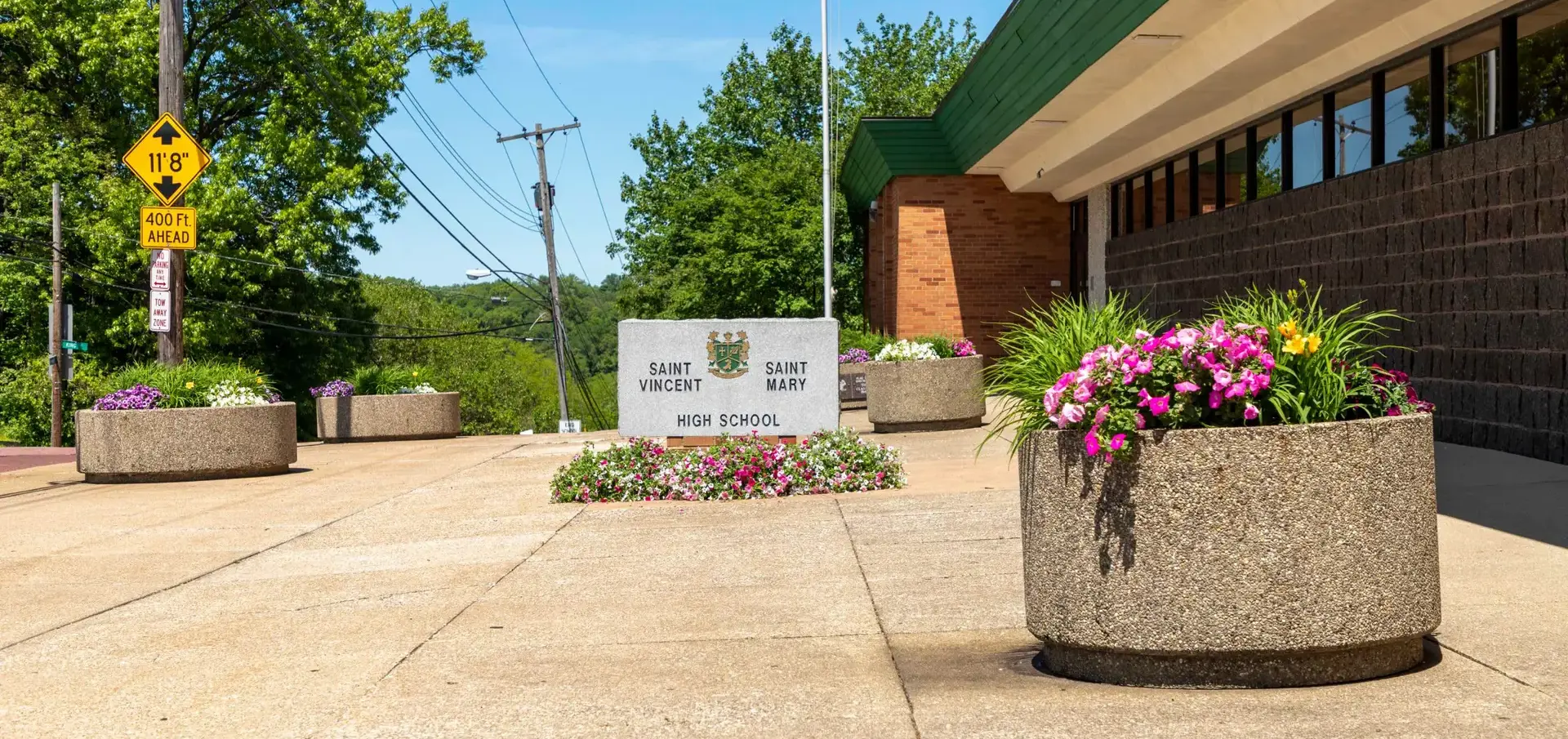 External photo of St Vincent St Mary High School building with granite sign and flower planters in foreground.