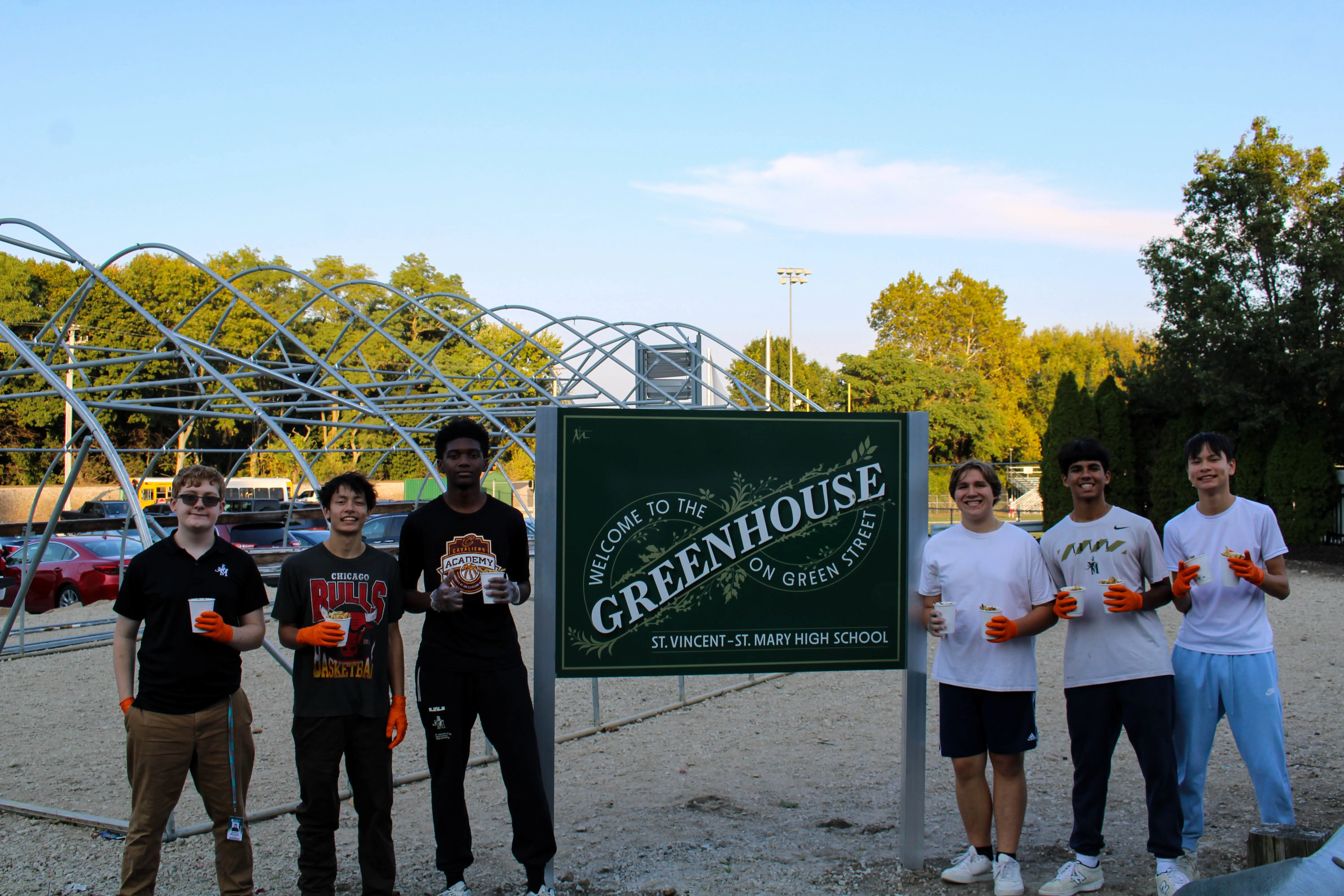 STVM students standing by sign reading 'Welcome to the Greenhouse on Green Street'.