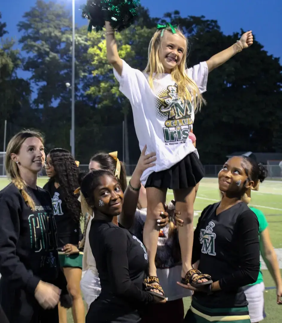 Club Irish attendee being held up by STVM cheerleaders, smiling elatedly.