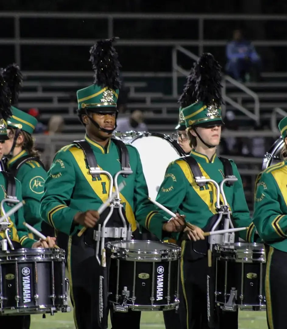 STVM marching band members playing drums on the sports field.
