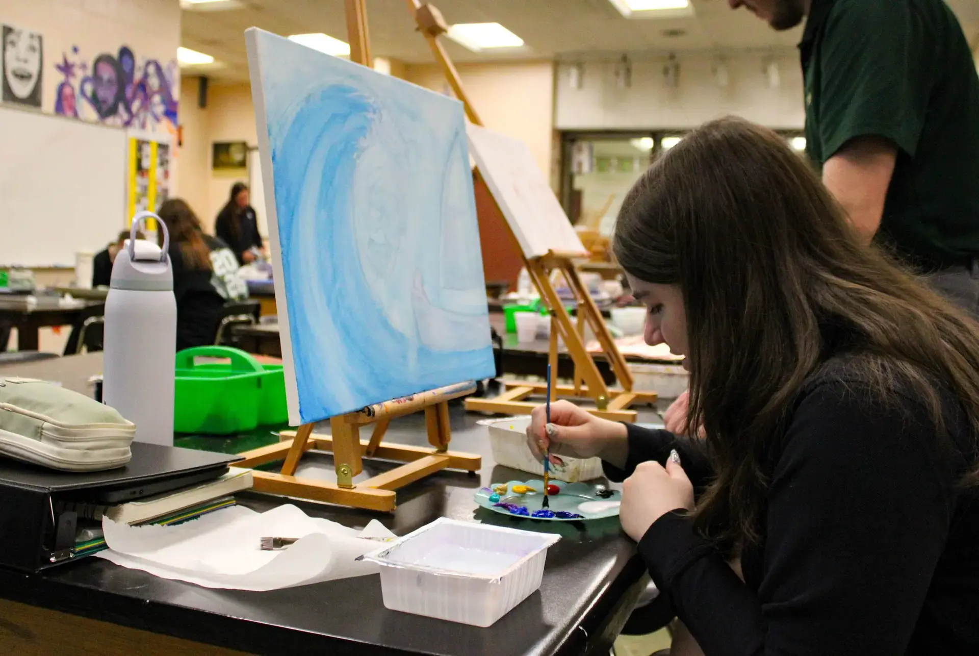 St. Vincent-St. Mary High School student painting an ocean scene in an art class.