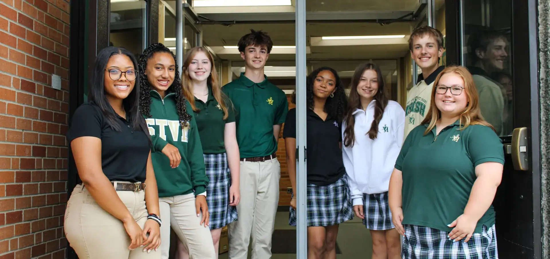 St Vincent St Mary High School students standing at the entrance to the school, smiling brightly.