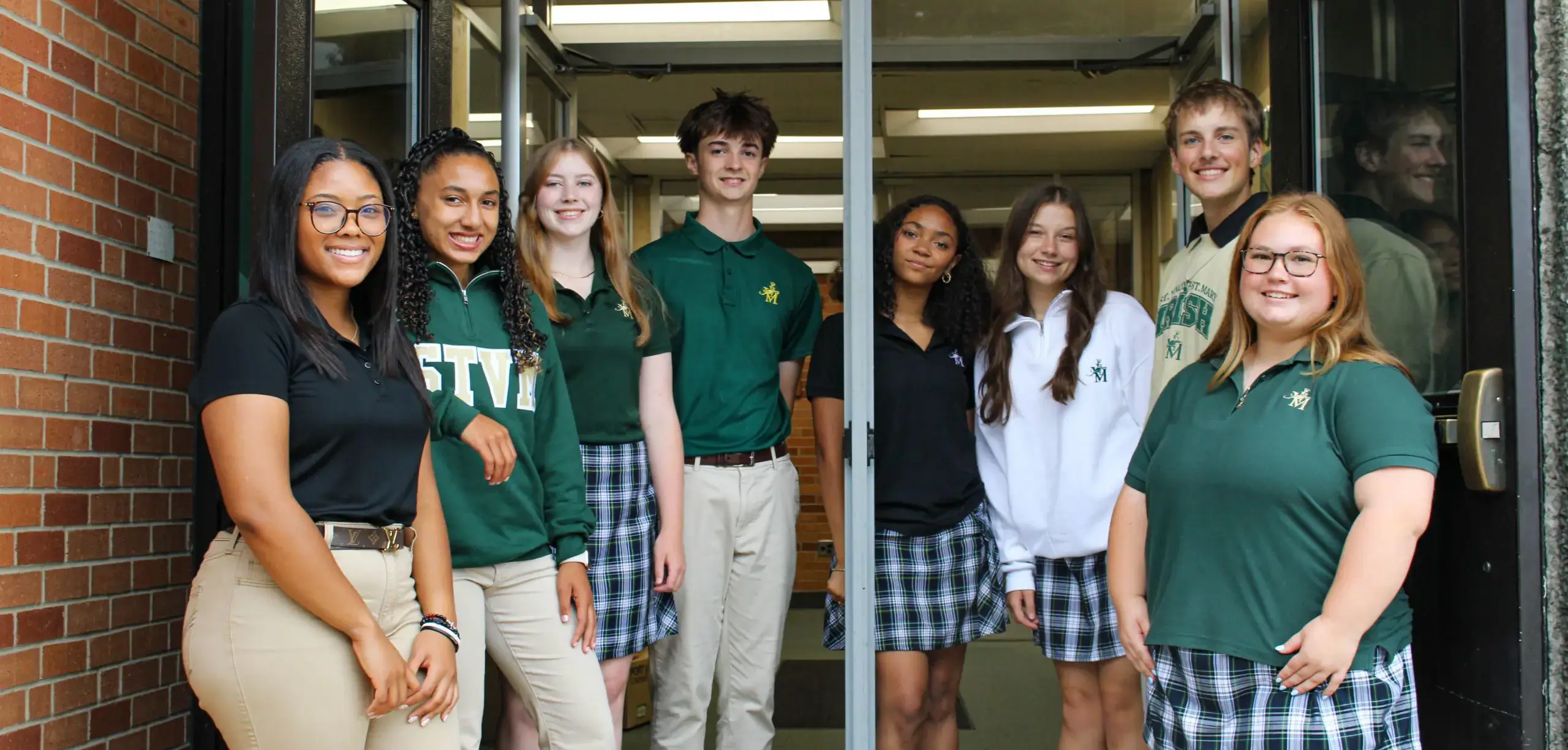 St Vincent St Mary High School students standing at the entrance to the school, smiling brightly.