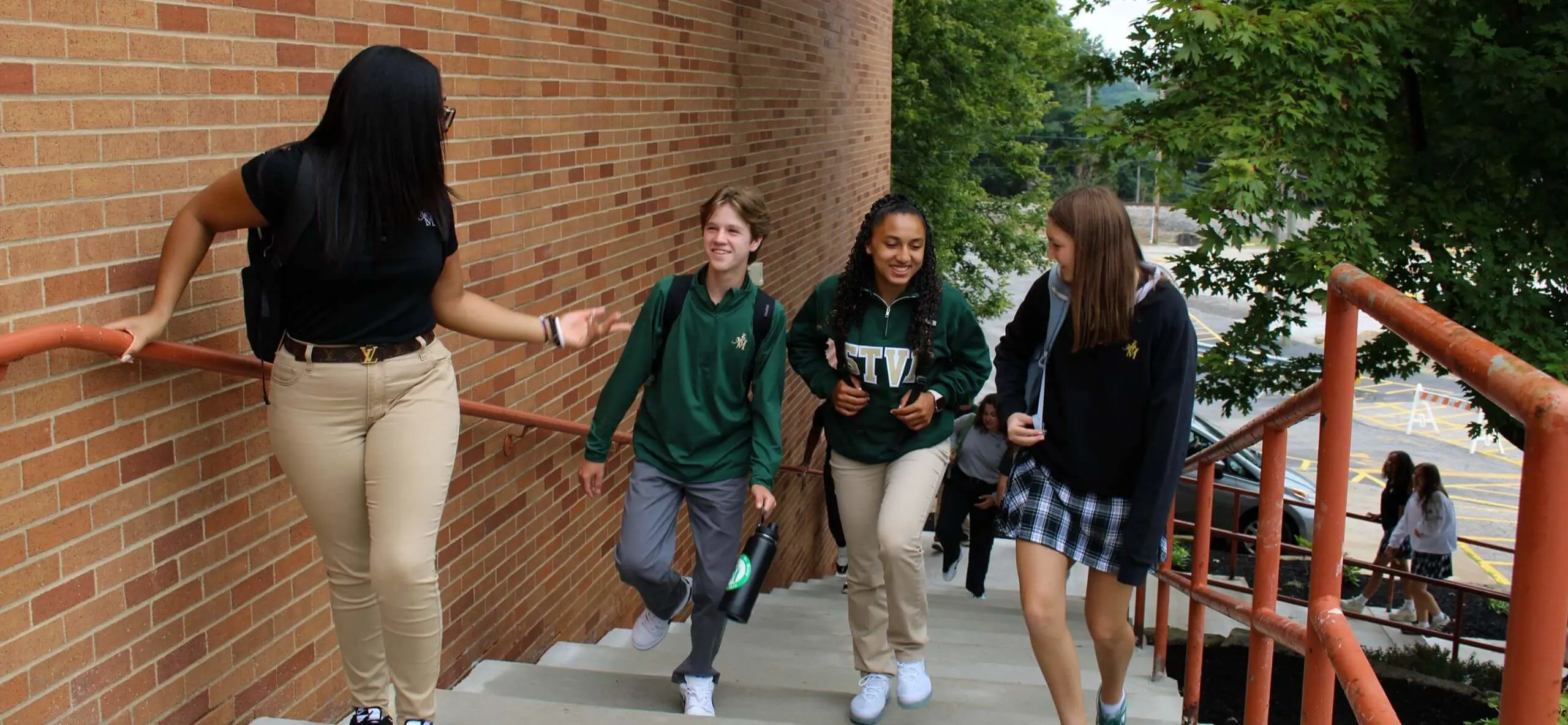 STVM students walking into school, carrying backpacks, laughing, talking.