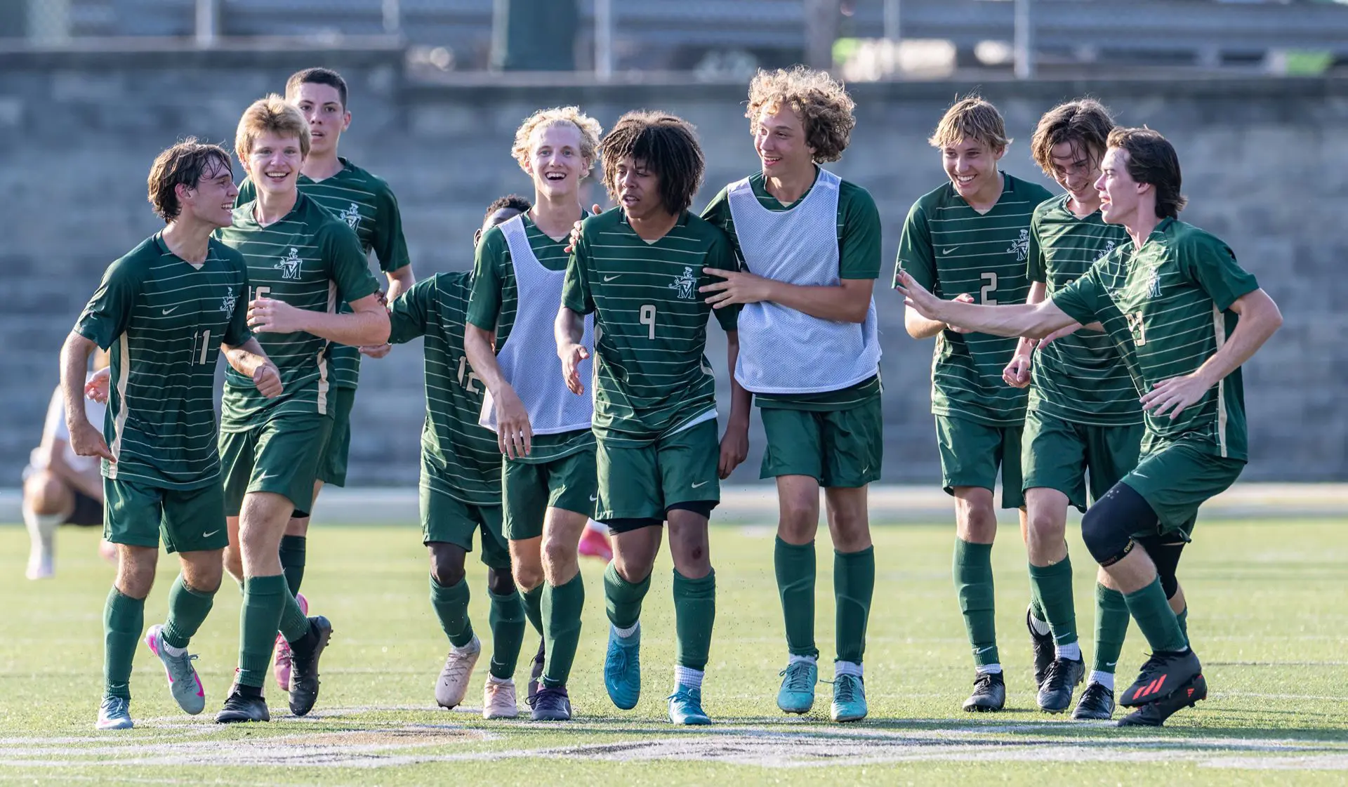 STVM soccer team on sports field, laughing, running.
