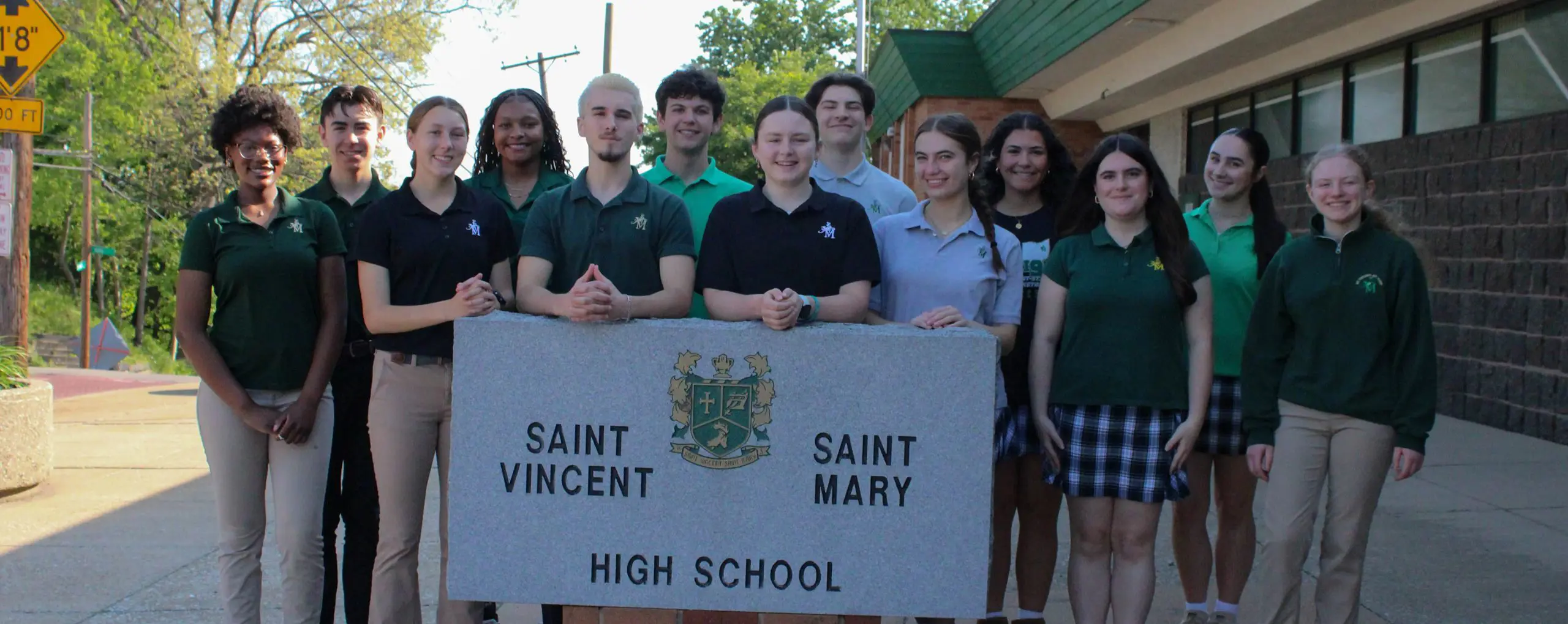 STVM student leadership standing with school sign.