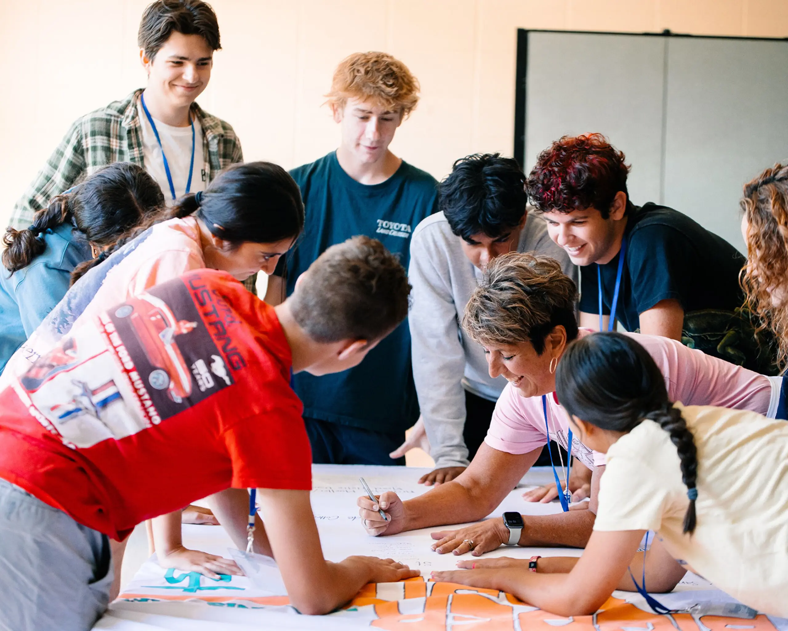 Students and an adult leader collaborating on a group activity around a table