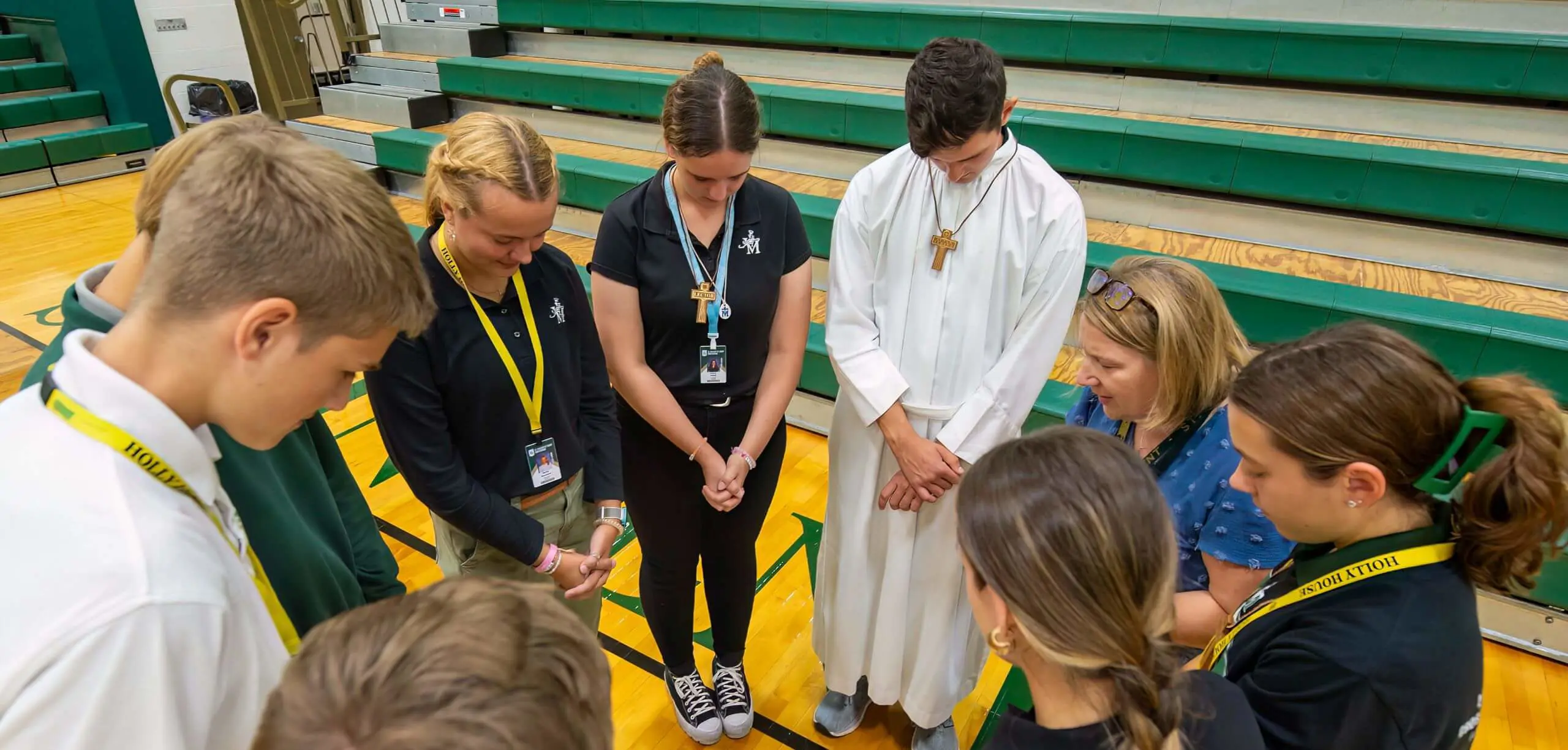 STVM students and teacher in a prayer circle in the gymnasium.