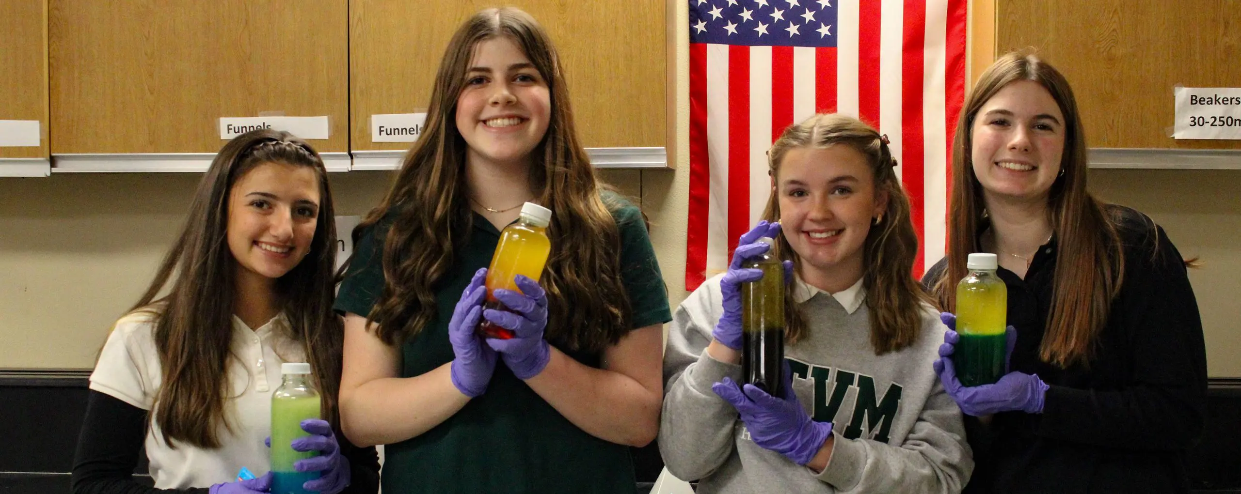 STVM students holding bottles of chemicals in a science class.
